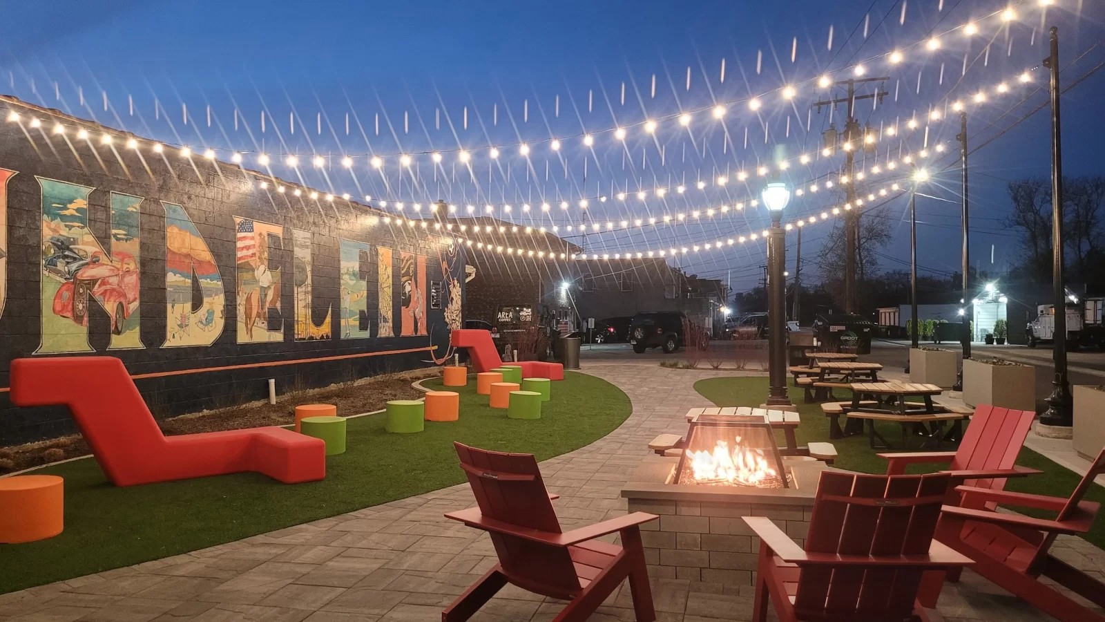 Mundelein mural and outdoor seating with string lights at dusk